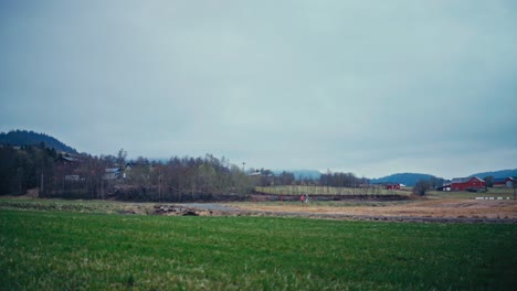 car passes on the road overlooking a rural village in norway. timelapse