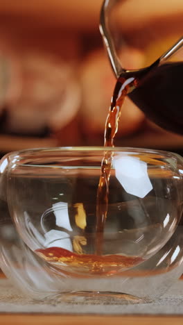 pouring tea into a double walled glass cup