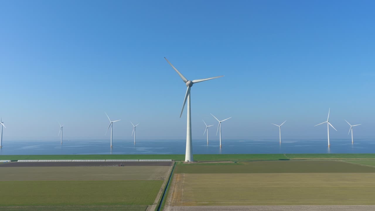 オランダにある大規模な陸上および洋上風力発電所の空撮。タービンが回転し、持続可能でクリーンな電力を生み出している。
