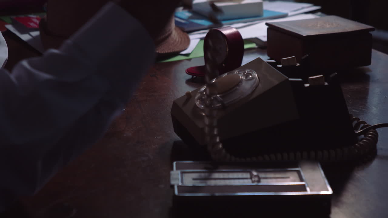 рука быстро и с нетерпением поднимает трубку ретро-ротационного телефона, а затем медленно вешает его