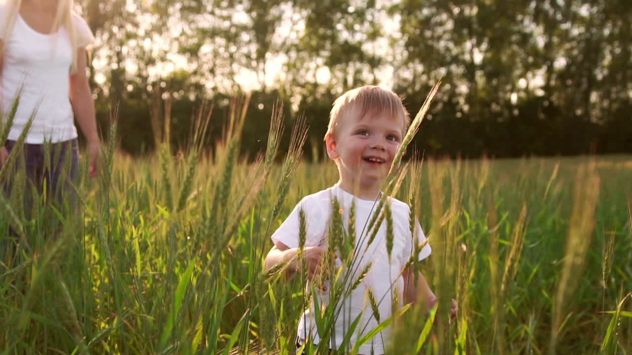 niño con camisa blanca caminando en un campo directamente hacia la cámara y sonriendo en un campo de púas