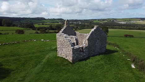 establishing aerial view capel lligwy ruined chapel on anglesey island green countryside coastline, north wales