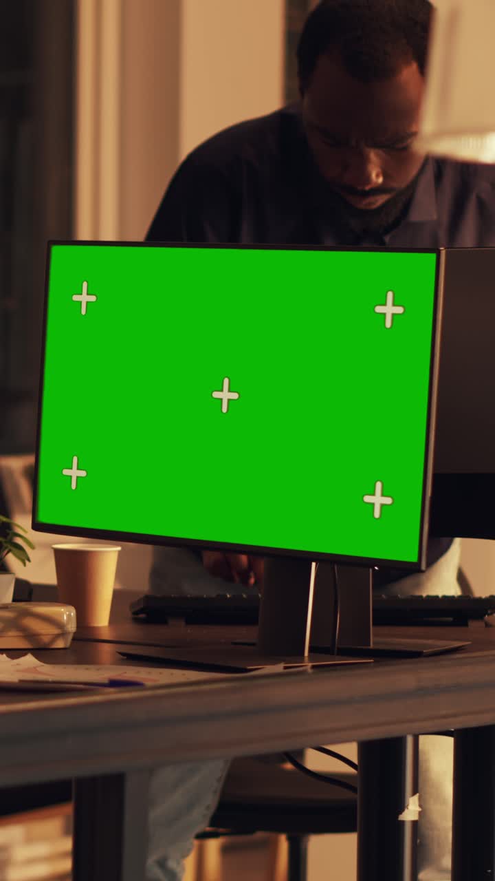 Vertical video: Young adult looking at greenscreen display on computer