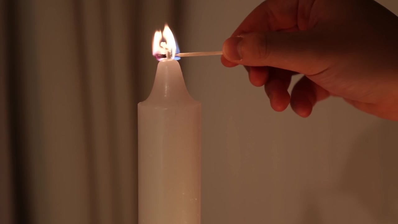 Gros plan macro extrême d'une mèche de bougie s'allumant avec une petite flamme bleue et blanche.