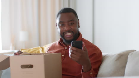 man unpacking a cardboard box and using a smartphone