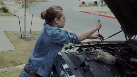 Woman-in-early-20s-checking-under-the-hood-of-a-truck-and-going-under-the-truck-to-find-and-fix-mechanical-problem