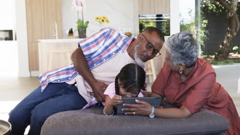 Biracial-grandparents-are-engaging-with-a-young-girl-using-a-tablet