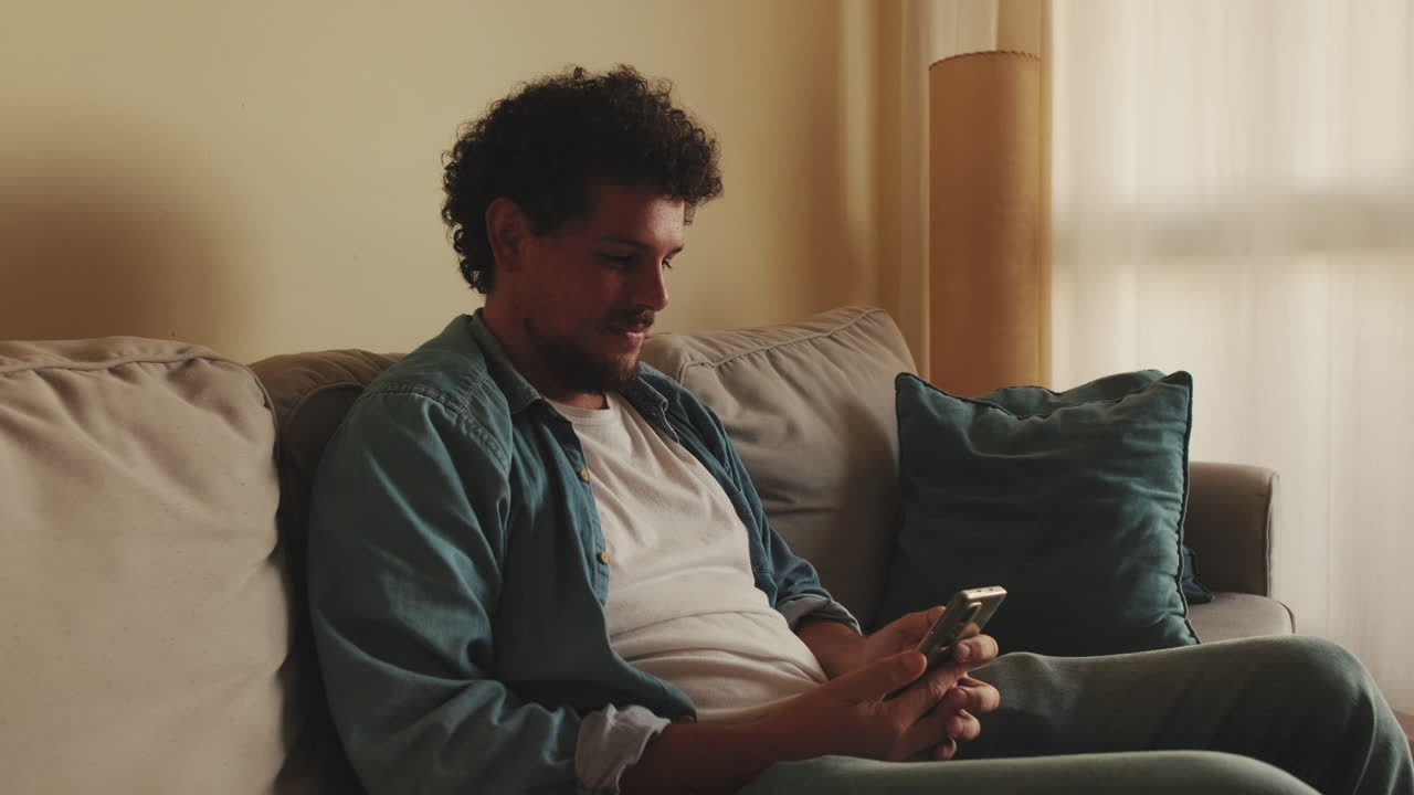 Man Relaxing on Couch with Smartphone
