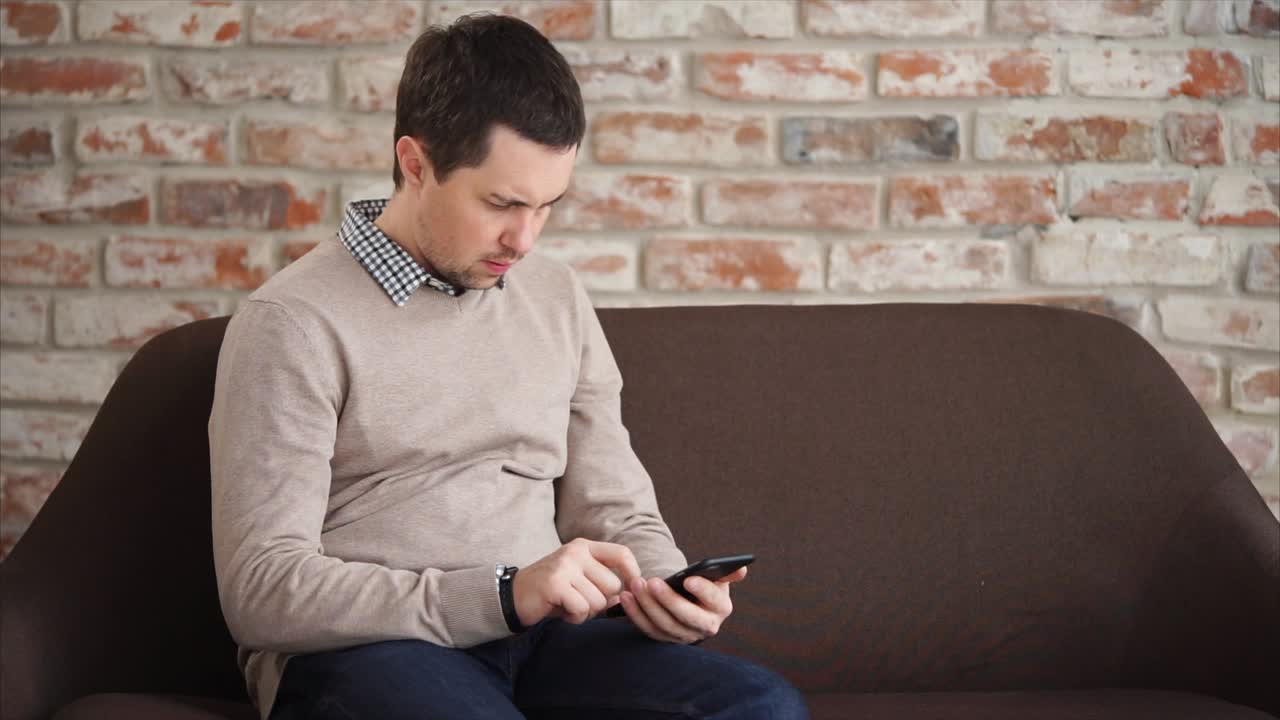 소파에서 스마트폰을 사용하는 남자