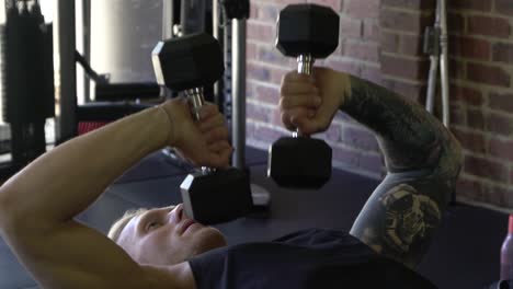 Tattooed-muscly-man-in-home-gym-working-out-close-up-inward-tricep-press