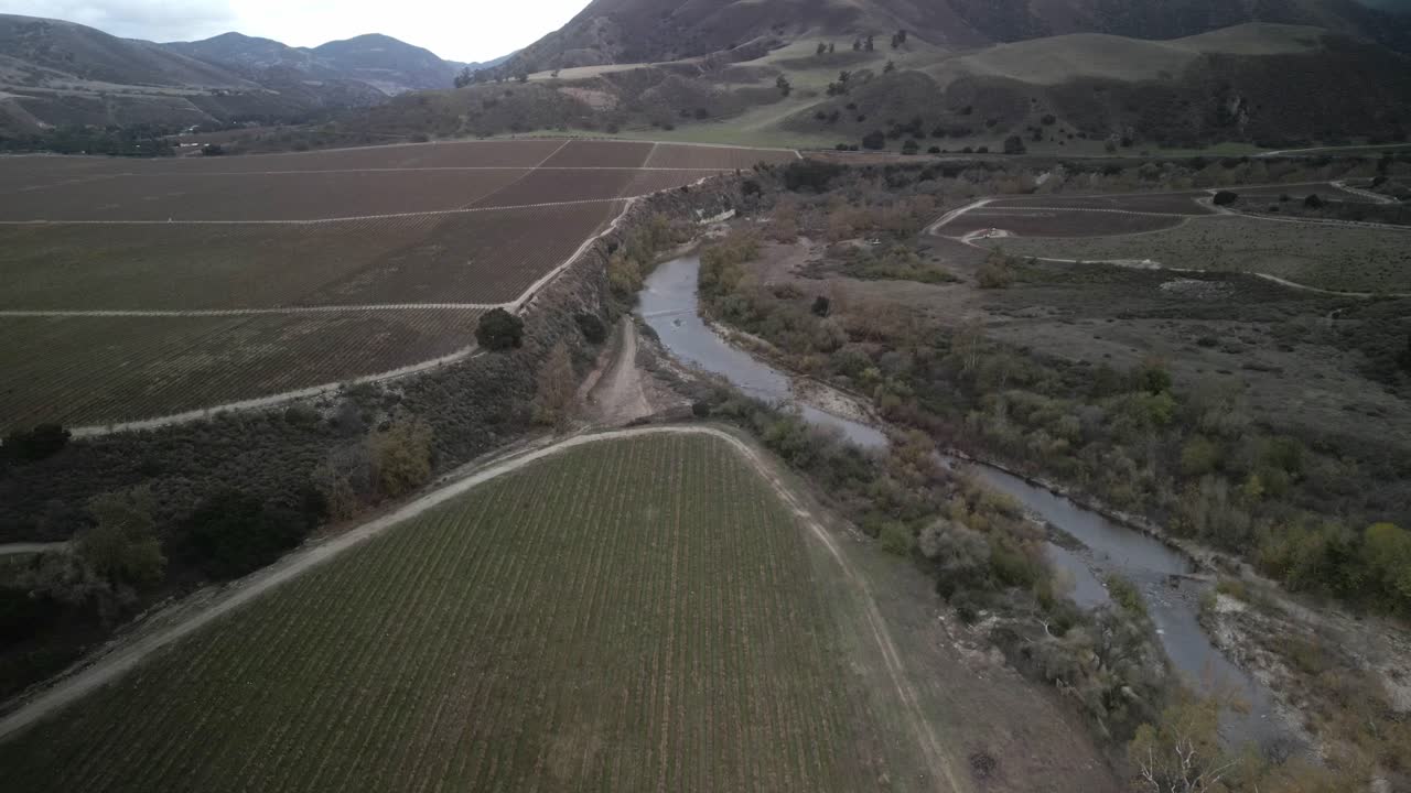 Arroyo seco river winding through vineyards and agricultural land in Greenfield, California, showcasing the interplay of nature and cultivation in the Salinas valley, drone establishing shot