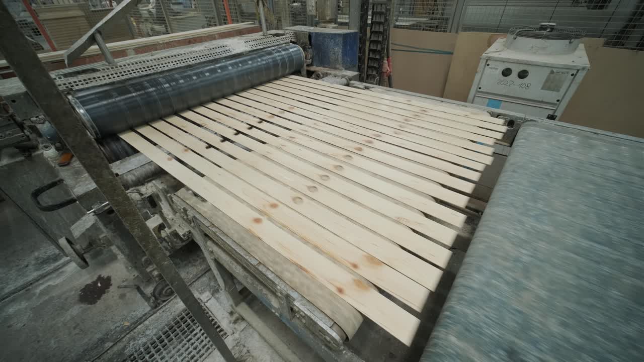 Trælister transporteres på et samlebånd på en fabrik.
