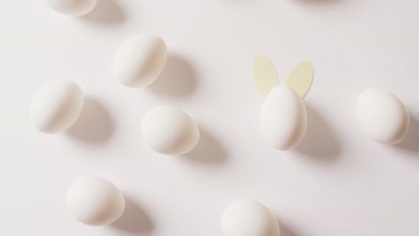 Multiple-white-easter-eggs-with-rabbit-ears-on-white-background