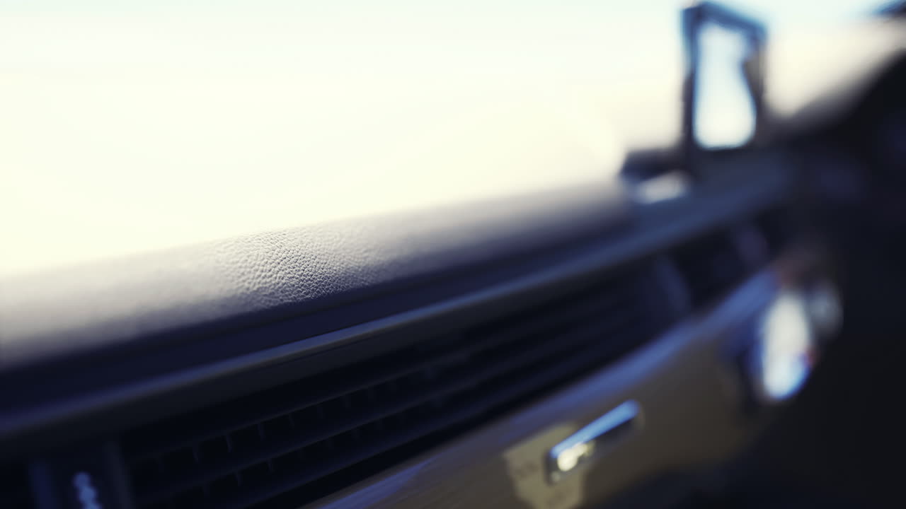 Primo piano degli interni di un'auto che mette in risalto i dettagli del cruscotto durante il tramonto