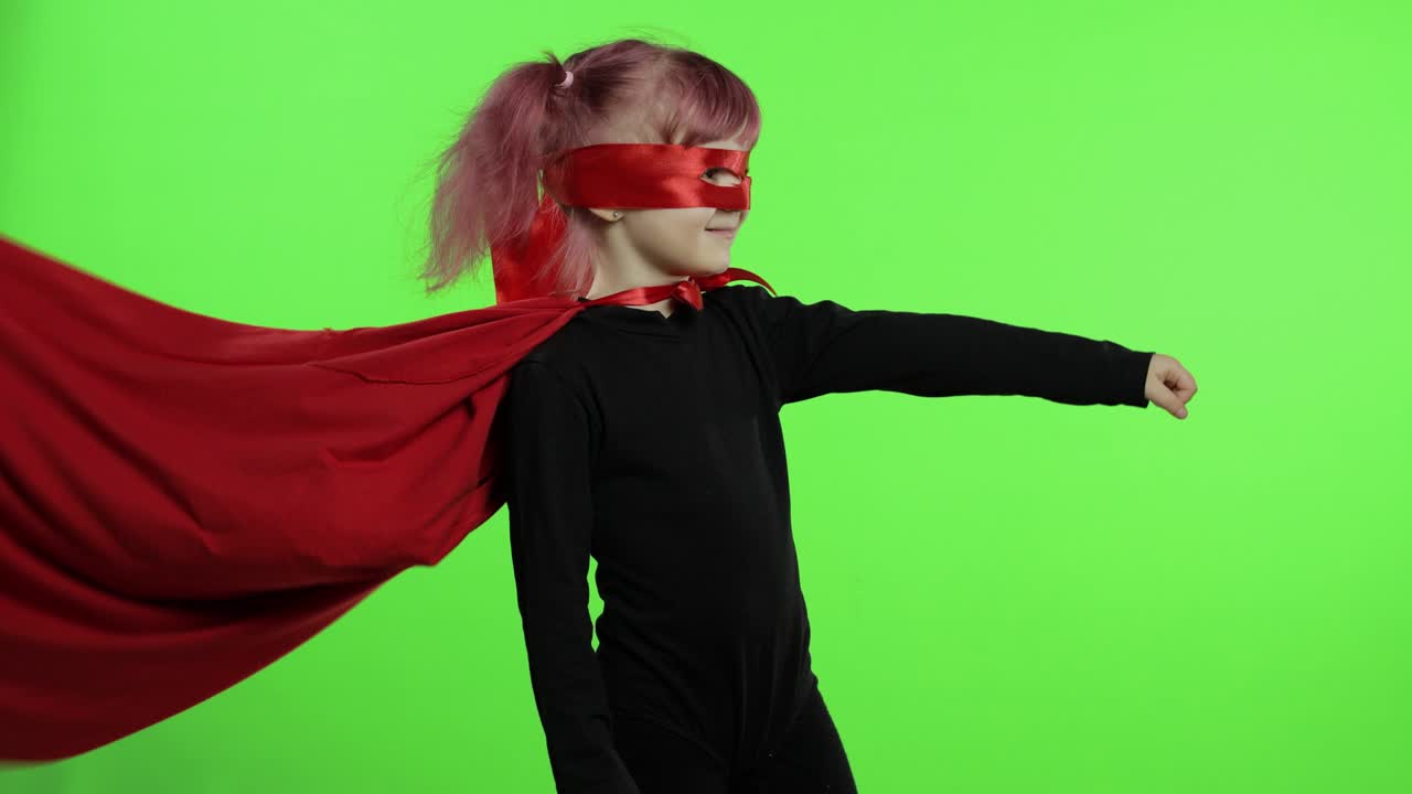 Funny child girl in costume and mask plays super hero. National superhero day