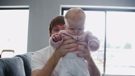 happy cheerful dad showing baby daughter at camera