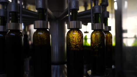 Empty-bottles-filled-up-with-red-wine-at-a-winery-production-line-in-Vignonet-France-made-of-green-glass,-Close-up-shot