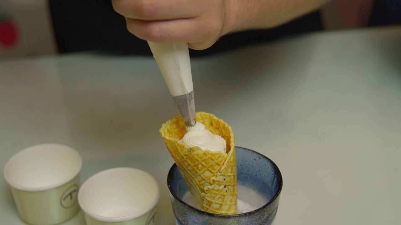 Montare lentamente panna densa su un cono waffle.