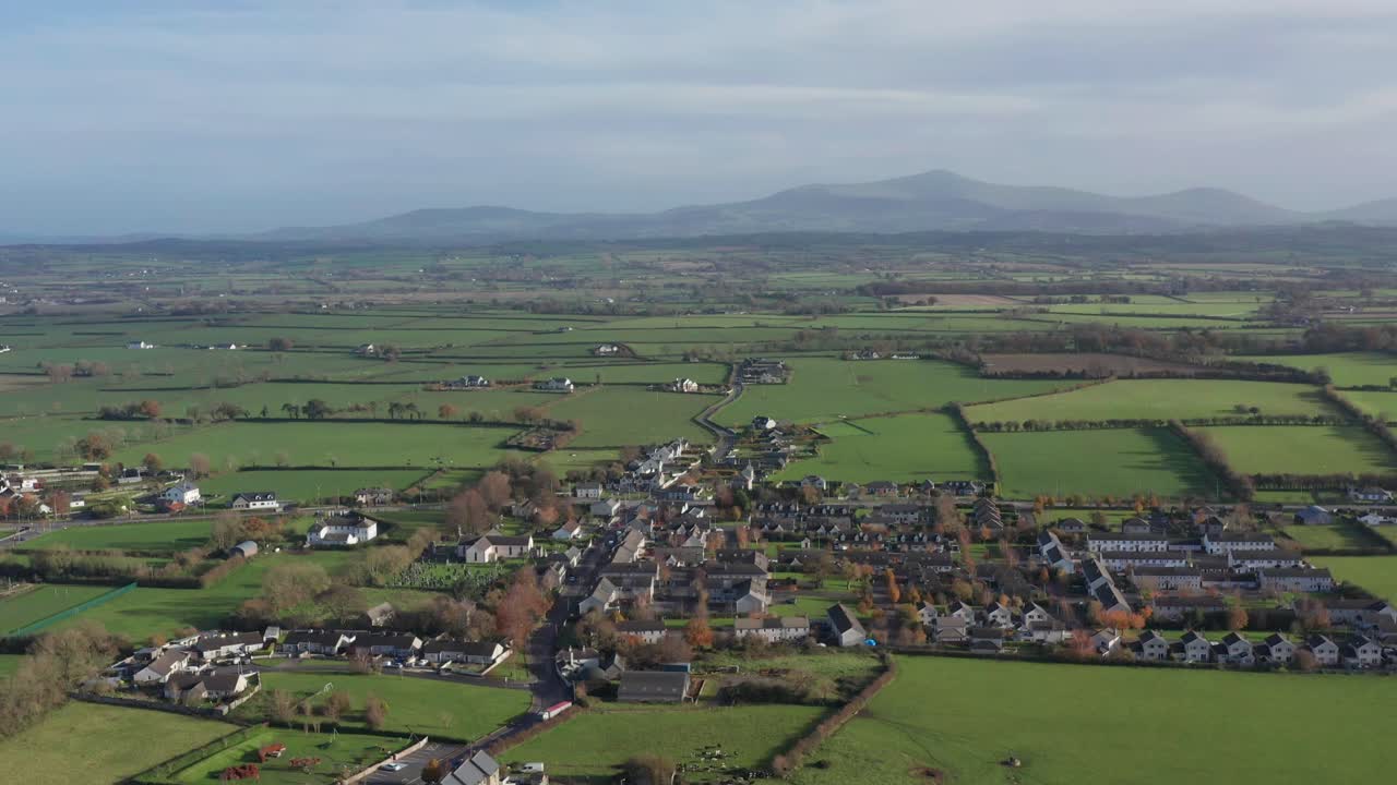 아일랜드 시골의 울창한 초록색 언덕에 자리 잡은 작은 아일랜드 마을을 드러내는 기울어지는 공중 촬영