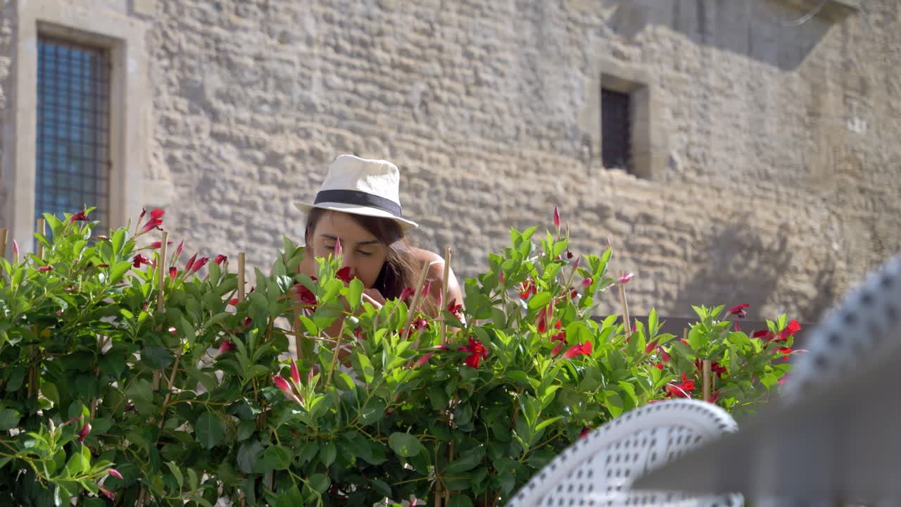 mujer caminando por la calle y luego se detiene porque quería oler las flores