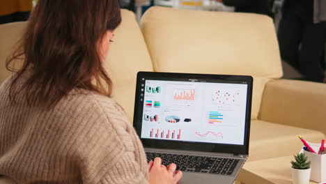 Close-up-of-back-view-young-entrepreneur-sitting-on-couch-in-office-using-laptop