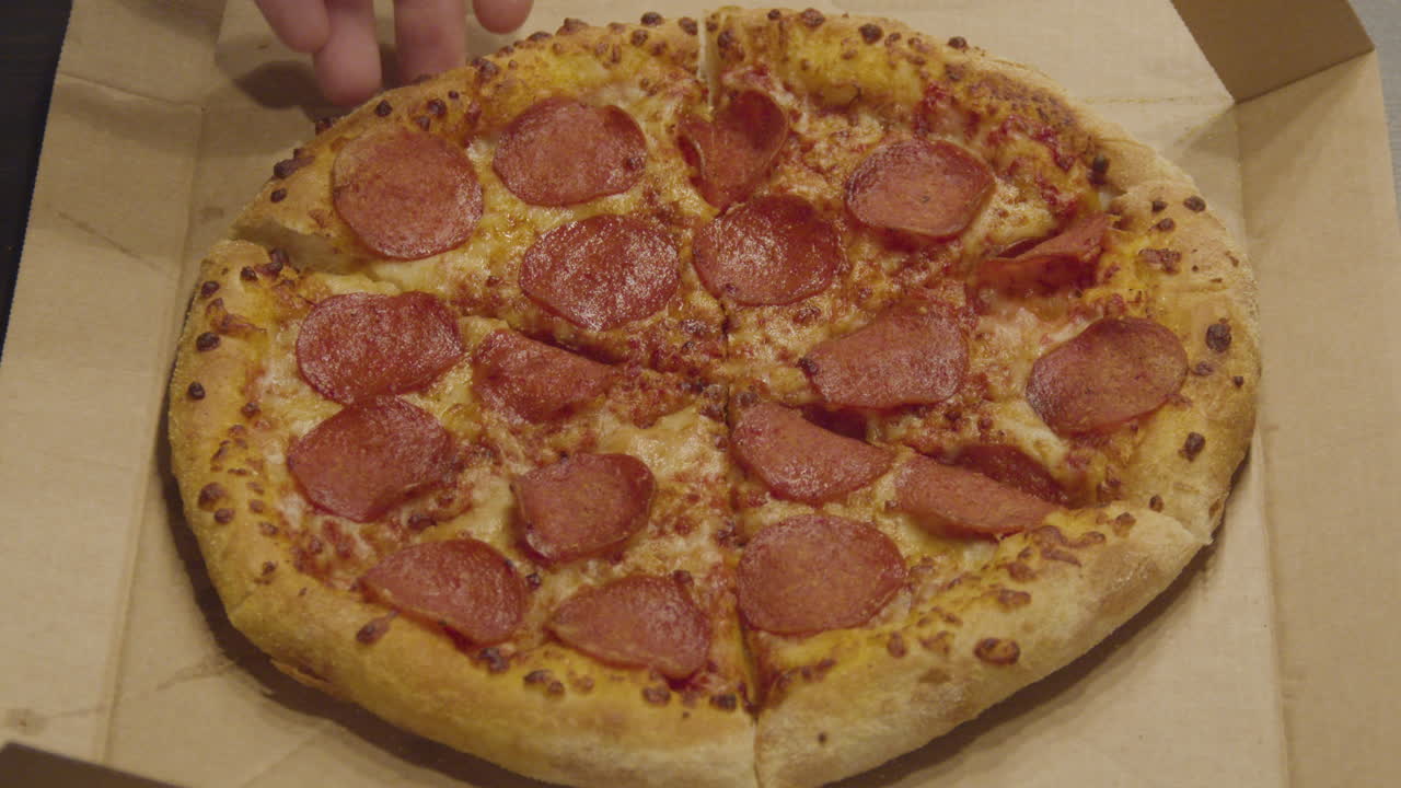 전체 피자에서 페퍼로니 피자 한 조각을 손으로 잡는 모습 - 중간