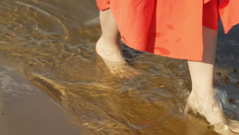 caucasian female in long skirt walking in shallow water - close up