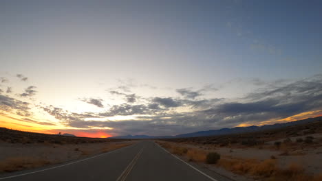 Conduciendo-Por-Una-Carretera-Del-Desierto-De-Mojave-Hacia-Las-Montañas-Y-La-Puesta-De-Sol---Punto-De-Vista-Del-Conductor