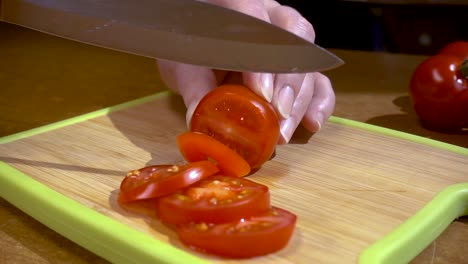 Knife-cuts-tomato-on-wooden-board-Slow-motion-with-rotation-tracking-shot.