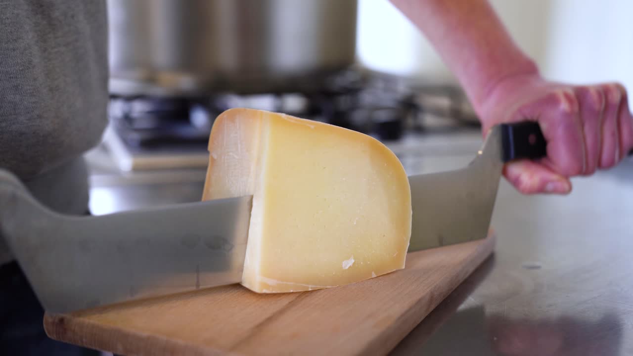 Close up at hands knife cutting goat cheese on display in wooden table, organic products