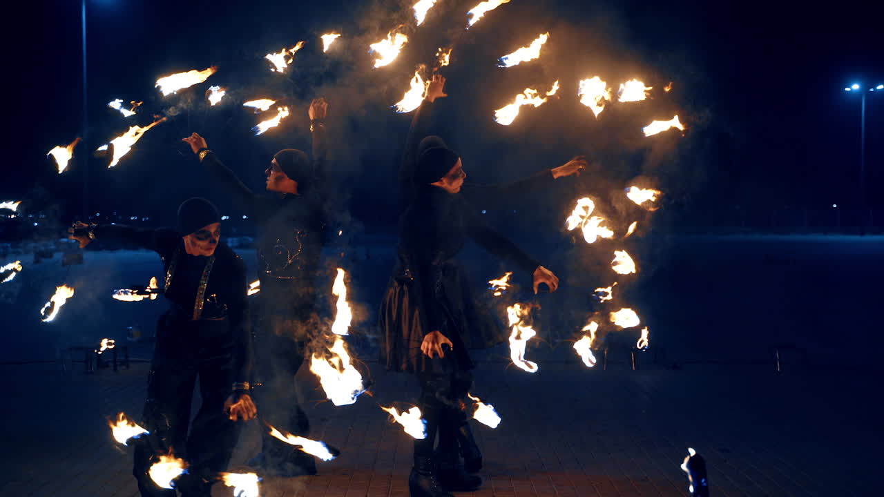 Beautiful dance with fire objects. Four people circle holding the burning props at night.