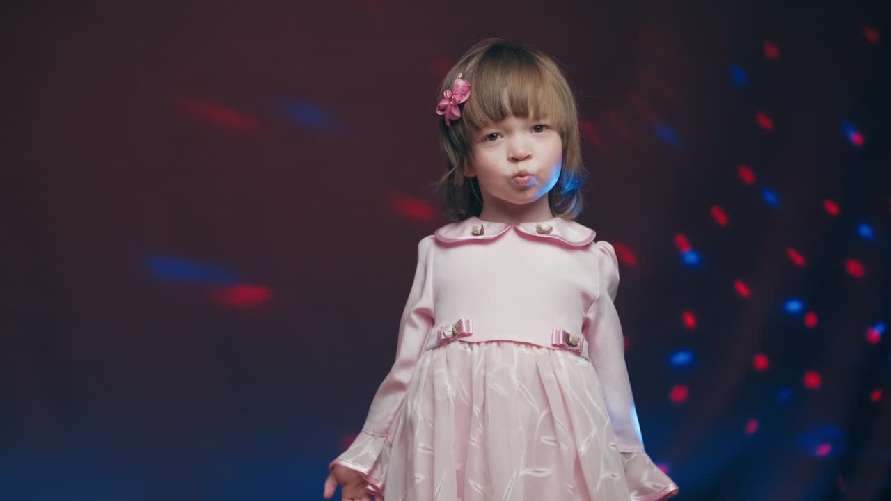 una niña linda en un vestido rosa vintage está girando en el baile y regocijándose
