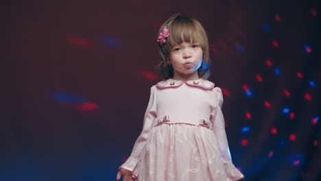 cute little girl in vintage pink dress is spinning in dance and rejoicing