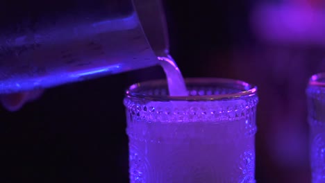 pouring mixed cocktail drink into glass, up close club party atmosphere