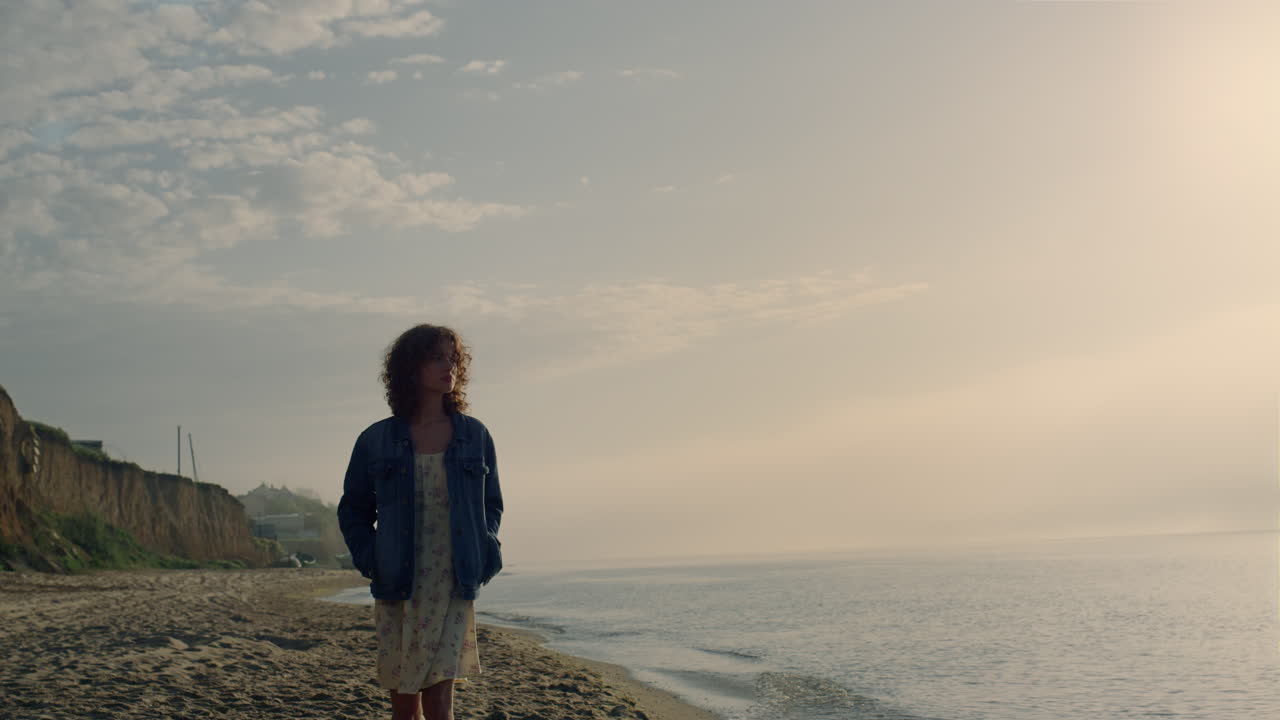 Romantic girl looking ocean view at sunrise. Dreamy woman walking on beach
