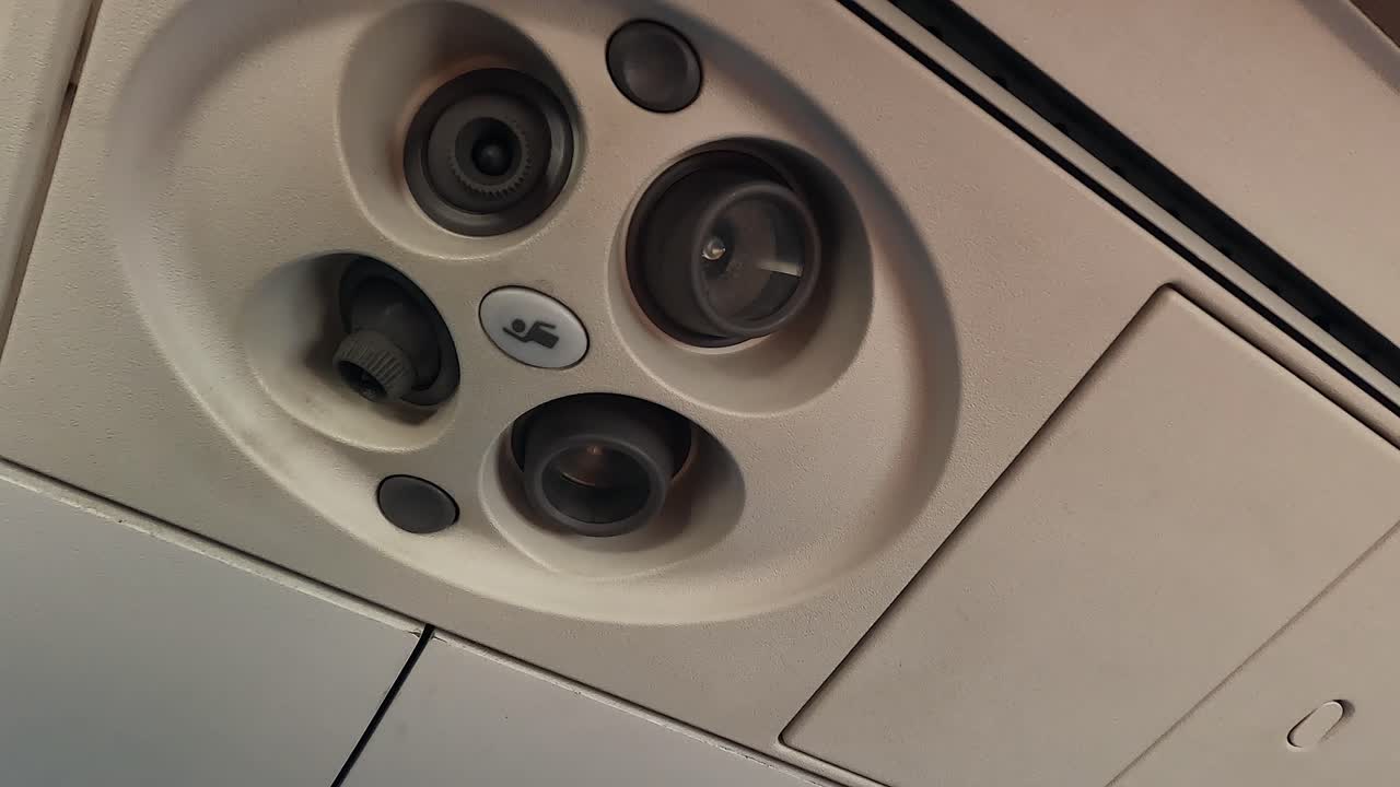 Left hand adjusts air flow and turns on cabin light in commercial jet