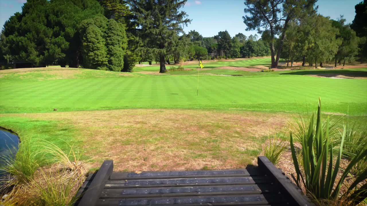 다리에서 보이는 노란색 깃발이 있는 무성한 녹색 골프 홀, 화창한 날