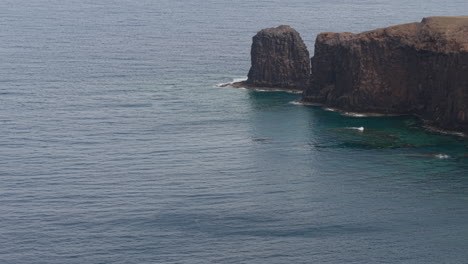 solitary traveler standing near cliff edge, overlooking dramatic roque partido rock formation in gran canaria's rugged coastal landscape with expansive atlantic ocean backdrop