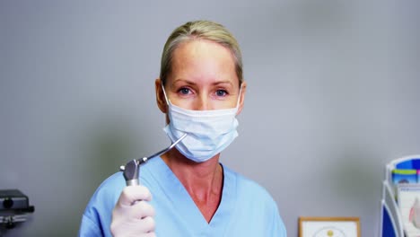 asistente dental sonriente sosteniendo una herramienta dental en la clínica
