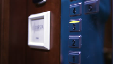 female hand pushing third floor button on panel into elevator car