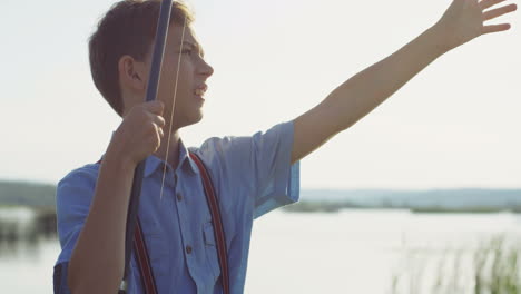 close-up view of teenage boy catching a fish from the lake with a rod and smiling in the morning