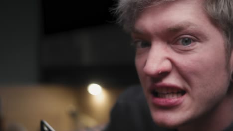 Holding-chopping-knife-along-nose-with-evil-laugh-by-young-crazy-psychopath-male-chef-in-an-elegant-black-shirt-with-an-alternative-look-and-tattoo-Modern,-fancy-looking-kitchen-Slow-Mo-Close-up