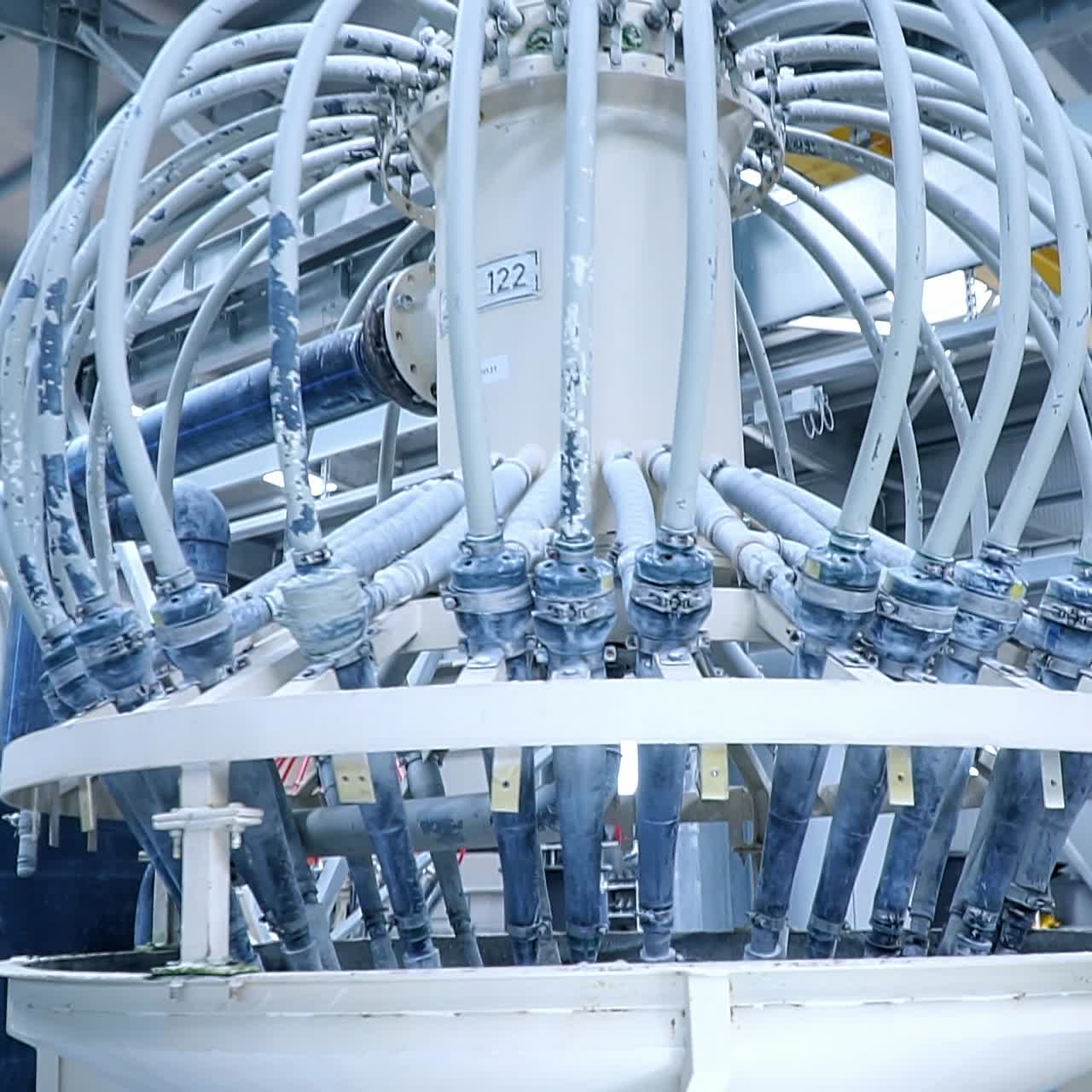White liquid coming out from the pipes attached to the tank. Automated kaolin clay production at the modern factory