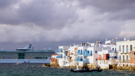 Hinter-Den-Atemberaubenden-Weißen-Gebäuden-Von-Mykonos,-Griechenland,-Ragt-Ein-Kreuzfahrtschiff-Auf