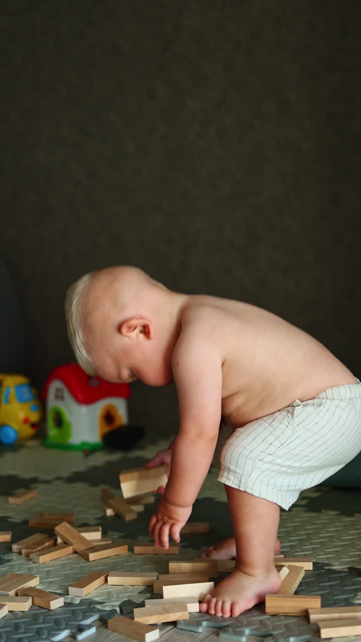 Un bambino piccolo gioca sul pavimento di casa. Il bambino gioca da solo a casa. Sviluppo del bambino