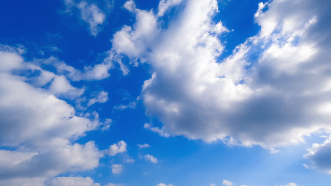 Light white clouds transform in the beautiful azure sky. Low angle view on the clouds lit with sun. Timelapse.