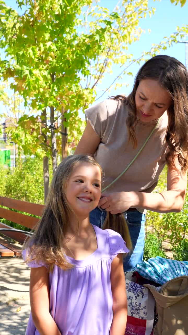 Mother braiding her daughter's hair outdoors
