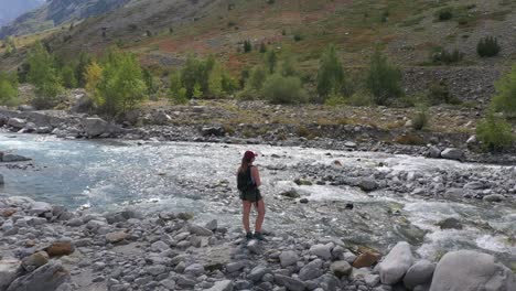 Gorgeous-wide-angle-on-a-young-Caucasian-woman-at-the-edge-of-a-powerful-river