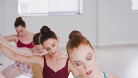 bailarinas de ballet caucásicas estirándose con una barra antes de una clase de ballet