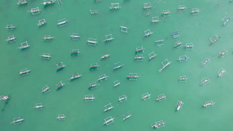 aerial view of indonesian traditional juking boats bobing on turquoise transparent waves near a tropical island of bali